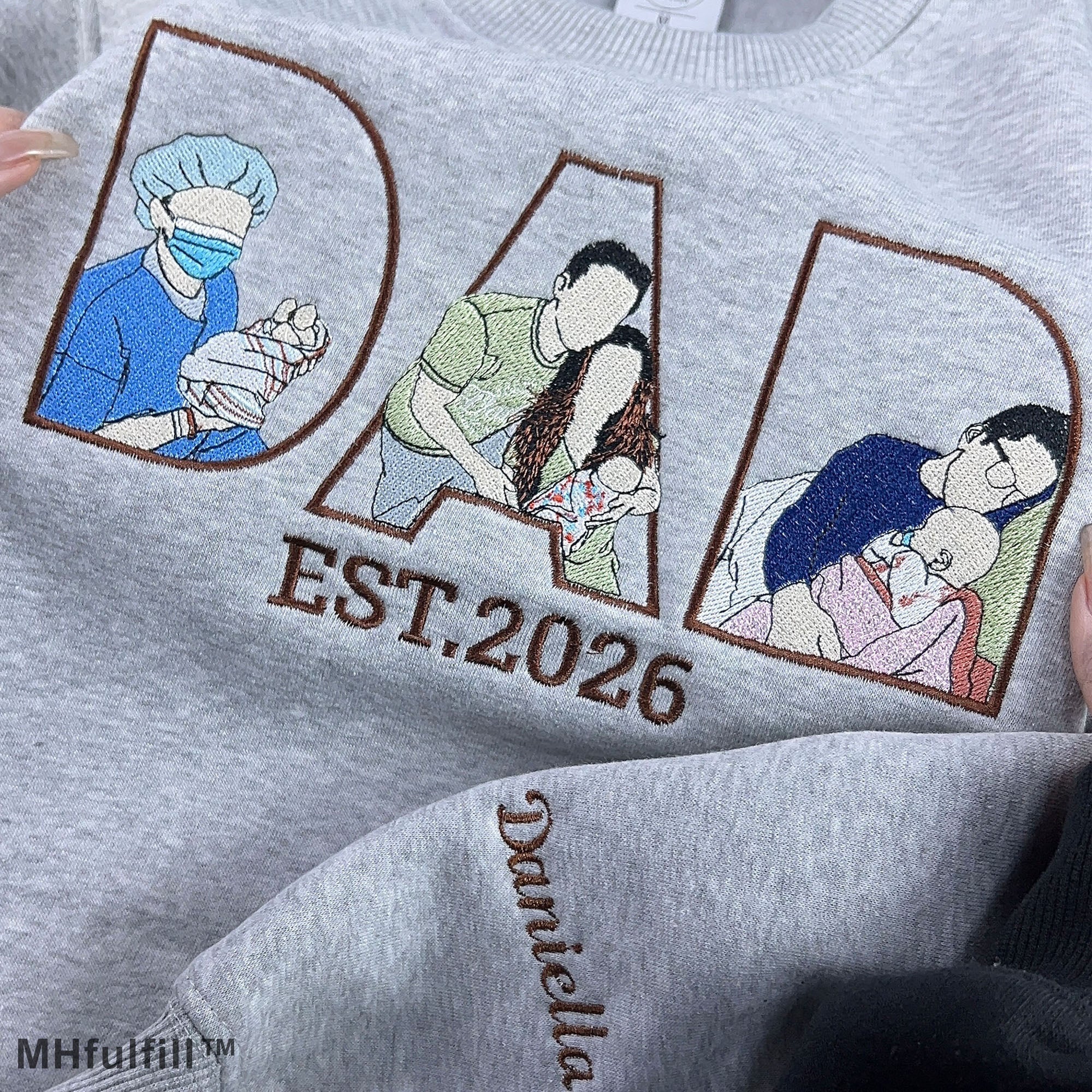 Detailed view of premium satin stitch embroidery showing a father hugging his baby on a personalized custom sweatshirt.