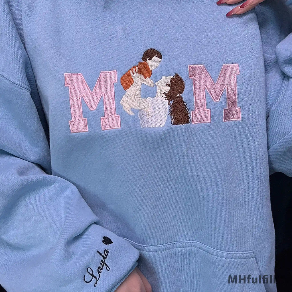 Examples of custom sleeve embroidery displaying children's names on the wrist cuff of a pastel hoodie.
