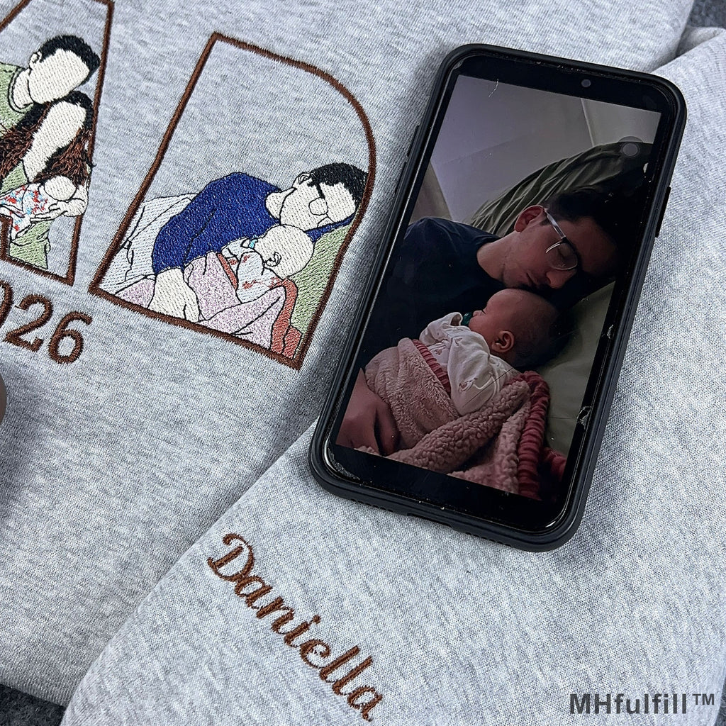 Personalized child name Daniella embroidered on the sleeve cuff of a grey custom dad sweatshirt.