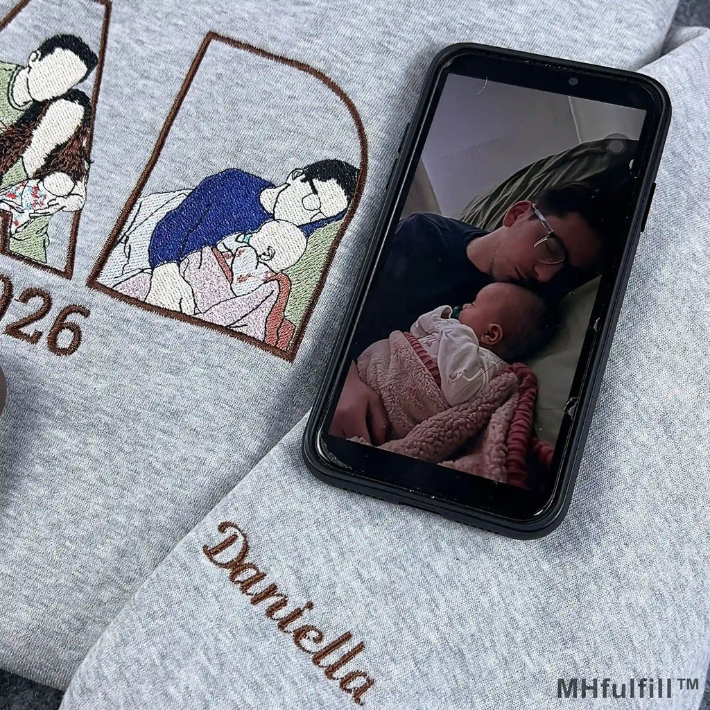 Personalized child name Daniella embroidered on the sleeve cuff of a grey custom dad sweatshirt.