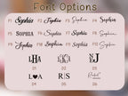 A digital graphic displaying font options for custom lettering, featuring the title 'Font Options' at the top and various serif and script style examples labeled F1 through F12 and D1 through D6 on a rounded beige card against a blurred pink background.