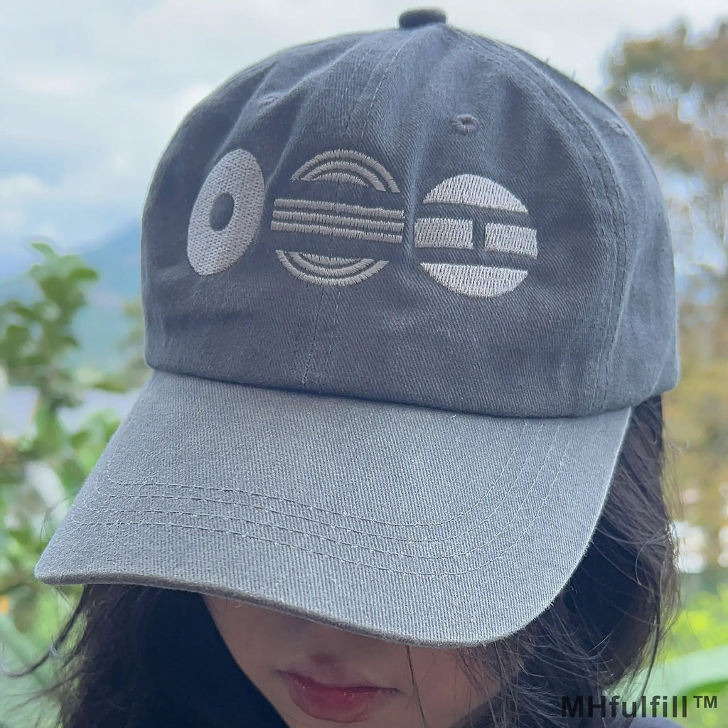 Close up of high quality white thread embroidery of abstract shapes on a distressed grey streetwear cap.