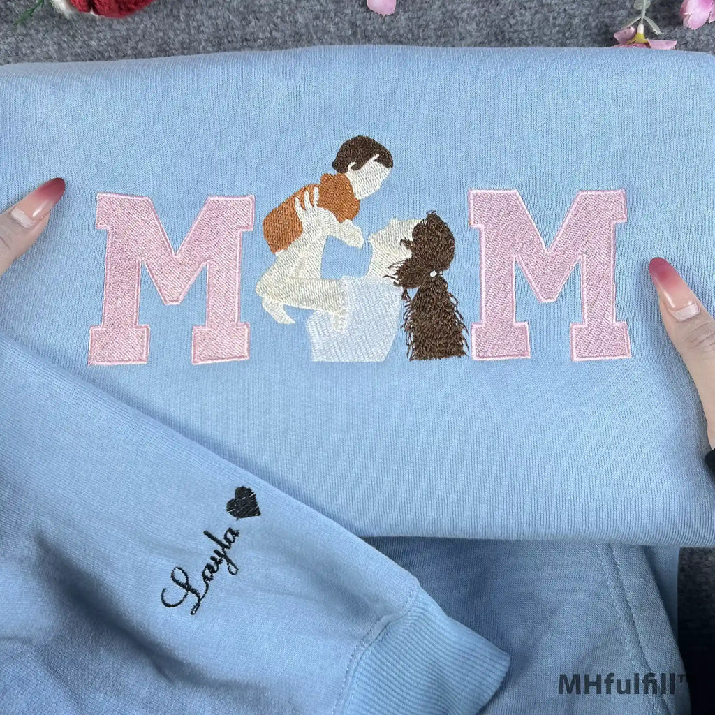 Detailed view of a custom motherhood portrait stitched inside pink varsity letters on a cozy sweatshirt.