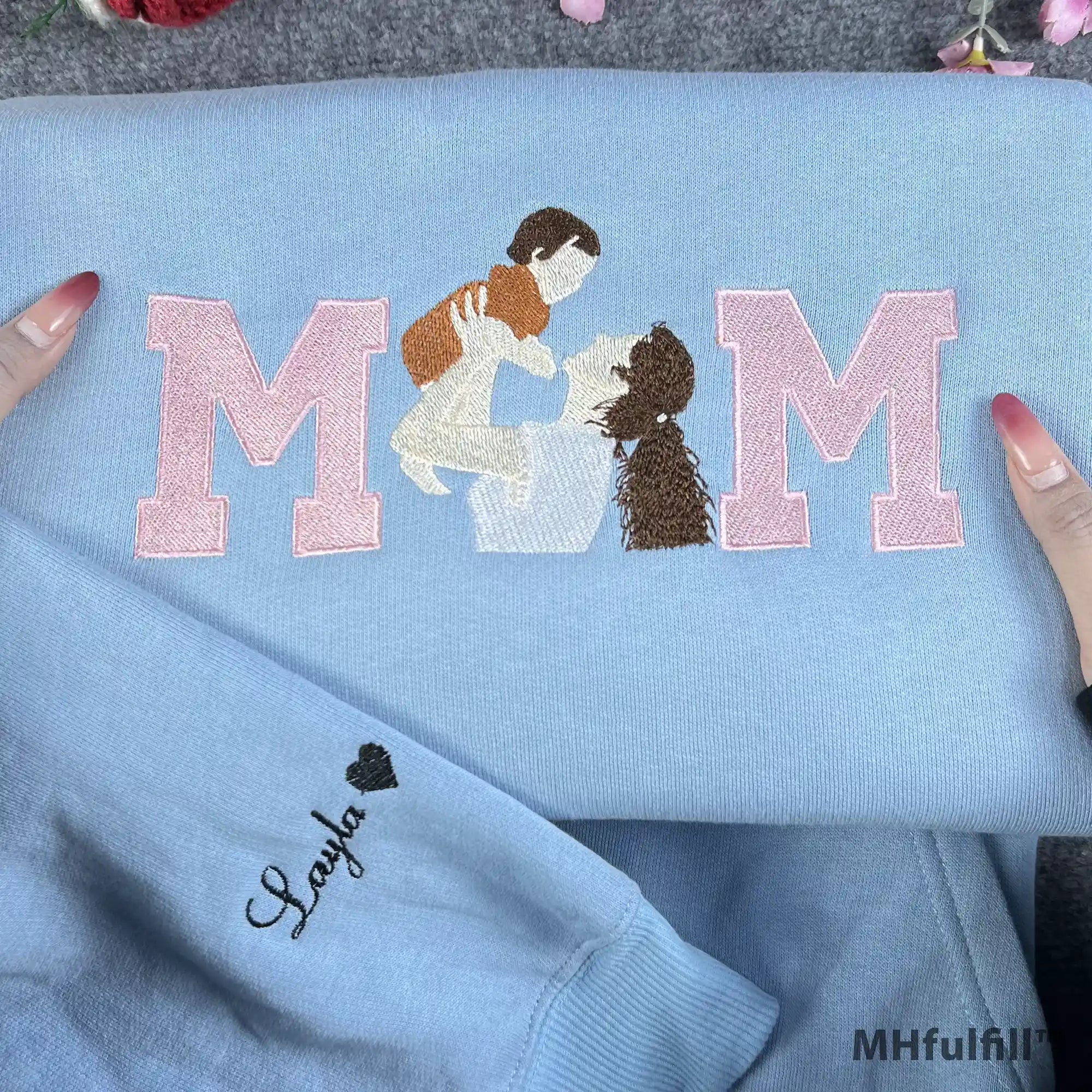 Detailed view of a custom motherhood portrait stitched inside pink varsity letters on a cozy sweatshirt.