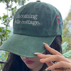 The MHFulfill custom embroidered green hat placed on a wooden bench at a cozy cottage campsite.