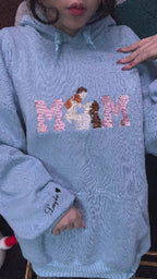 A woman holding a personalized light blue mama crewneck sweatshirt with high-quality custom thread embroidery.
