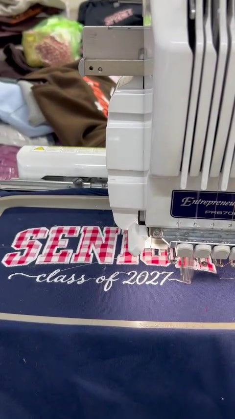 Embroidery process of a custom Senior 2027 appliqué sweatshirt with personalized sleeve name